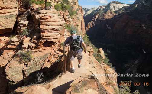 Picture of hiker on ledge holding a chain bolted to the wall of the canyon - Angel's Landing trail